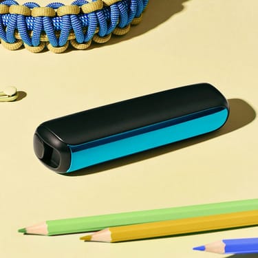 Akcesorium panelu przedniego Ploom AURA w kolorze oceanicznym przymocowane do urządzenia na biurku.
