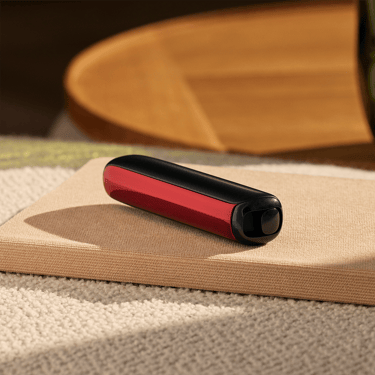 Akcesorium do panelu przedniego Ploom AURA w kolorze Lava Red przymocowane do urządzenia na stole.