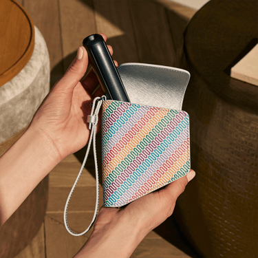 Dłoń wyjmująca urządzenie Ploom AURA Jet Black z etui Ploom Duo z wielokolorowym